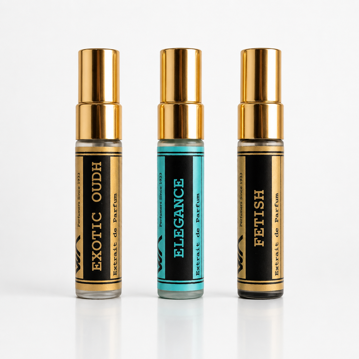 Three perfume roller bottles with gold caps are lined up on a white reflective surface. The left bottle is labeled 'EXOTIC OUDH', the middle bottle is labeled 'ELEGANCE' with a turquoise label, and the right bottle is labeled 'FETISH'.