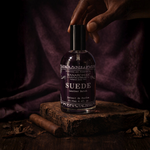 Bottle of 'Suede' perfume by Wanarom on a wooden surface with a dark background